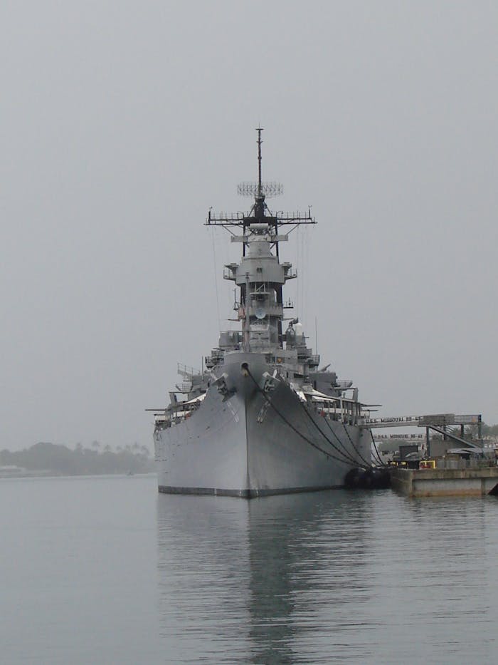 Home A historic battleship moored at Pearl Harbor, captured on an overcast day, symbolizing naval history.