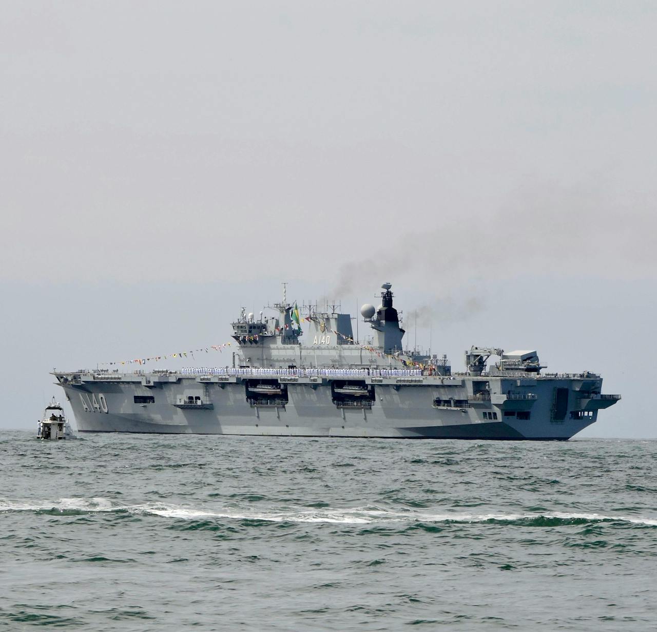 Offerings Military aircraft carrier sailing on ocean with visible smoke.